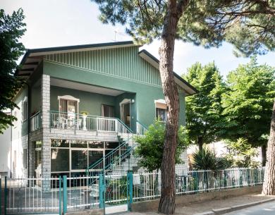 Casa verde a due piani con giardino e balcone.