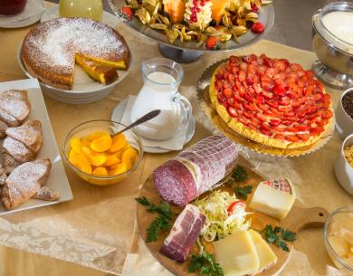 Petit-déjeuner avec pâtisseries, fruits, charcuterie, fromages et céréales.