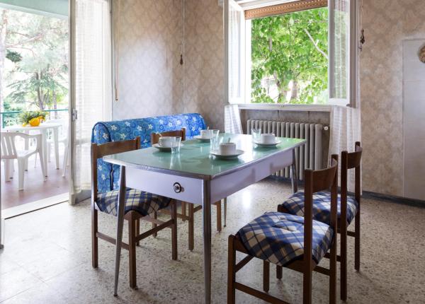 Cucina luminosa con tavolo vintage e sedie a quadri.